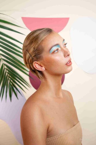 A photograph of a model with striking blue eye makeup in front of a minimalist background of clean, geometric forms, showcasing the harmonious blend of classic beauty and contemporary style.