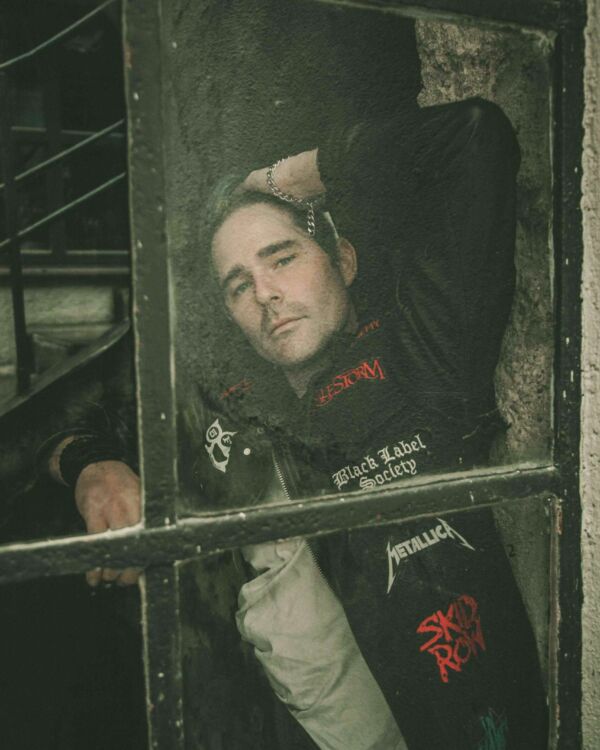 A portrait photograph with a dark, artistic retouch, featuring a metal enthusiast leaning in from the other side of a window, willingly participating in the metal community, symbolizing the dedication and unity of metal enthusiasts.